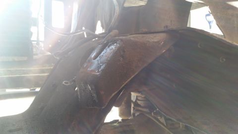 1985 Ford Bronco - Close-up view of rusty vehicle frame and suspension components, with a watermark for SuperMotors.net.