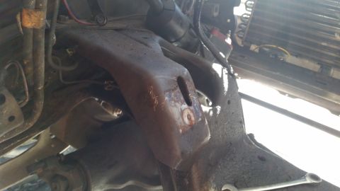 1985 Ford Bronco - Close-up view of a heavily rusted engine mount bracket, likely from an older vehicle undergoing maintenance.