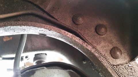 1985 Ford Bronco - Underside view of vehicle frame with brake lines and rivets visible.