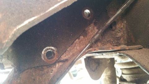 1985 Ford Bronco - This image shows a heavily rusted section of a vehicle's frame, with a brake cable visible.