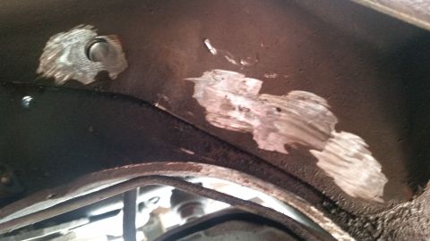 1985 Ford Bronco - Underbody metal repair patches are visible on a dark surface, possibly from a vehicle's frame.