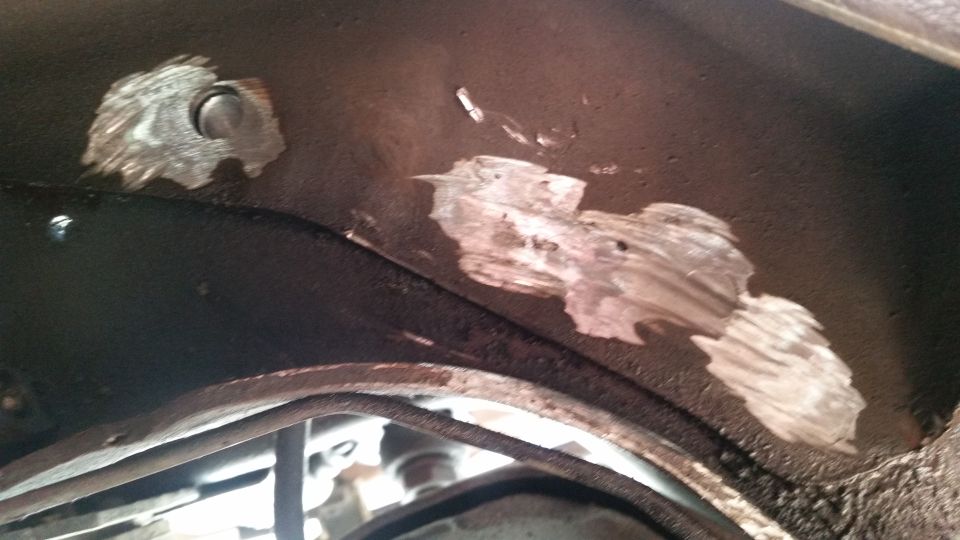 Patches of metal repair on a dark underbody surface, with some bolts visible