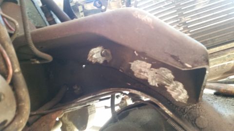 1985 Ford Bronco - Close-up view of a heavily rusted vehicle frame, showing signs of repair and exposed wiring.