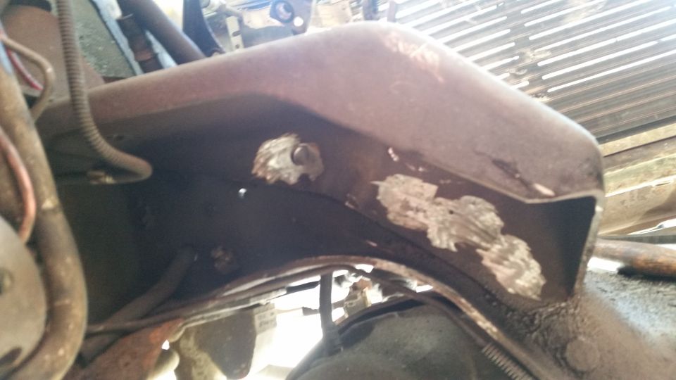 Rusty vehicle frame with visible metal patches and wiring