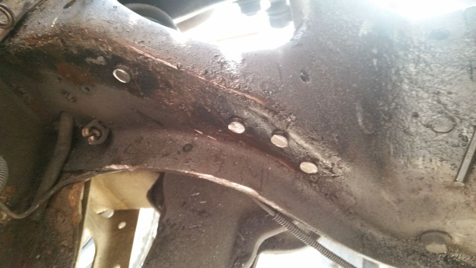 Close-up of a heavily rusted metal frame section with several bolts visible