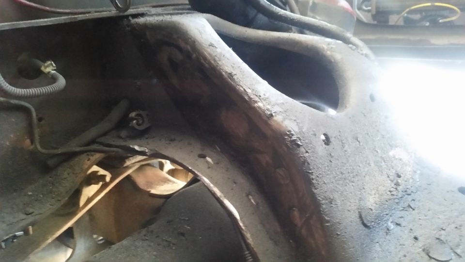 Close-up of heavily rusted metal frame component with wires attached
