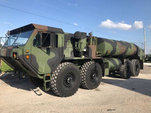 1992 Ford Bronco - This military fuel truck is parked outdoors under a blue sky with scattered clouds.