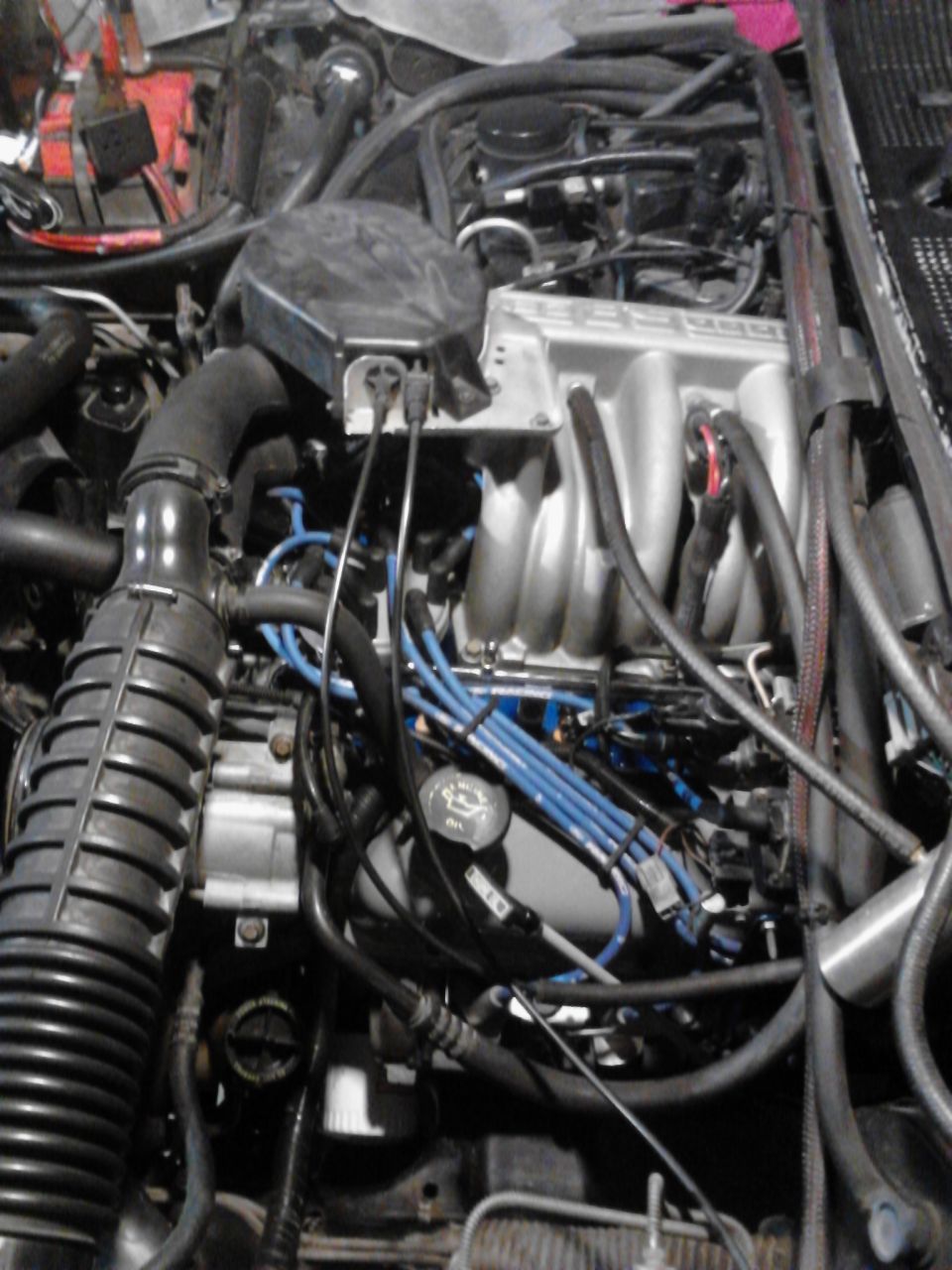 Engine bay with silver intake manifold, black air intake hose, and blue spark plug wires