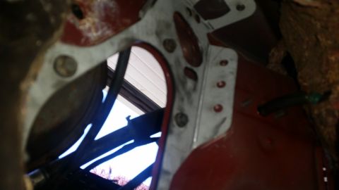 1985 Ford Bronco - This is a close-up view of a metal bracket attached to the red frame of a vehicle, with wires visible.
