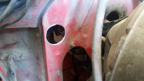 1985 Ford Bronco - This image shows a section of red painted metal with holes cut into it, possibly for wiring or components.