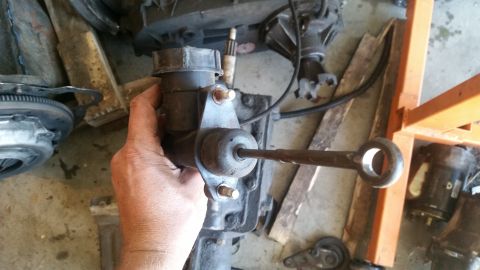 1985 Ford Bronco - A clutch master cylinder assembly is held in a hand, with various transmission components visible in the background.