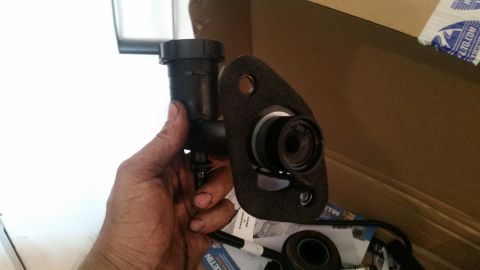 1985 Ford Bronco - Clutch master cylinder assembly being held, likely for a ZF transmission swap, with "SUPERMOTORS.NET" visible on packaging.