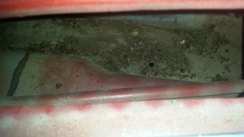 1985 Ford Bronco - Debris and dirt accumulated in a vehicle's interior cavity.