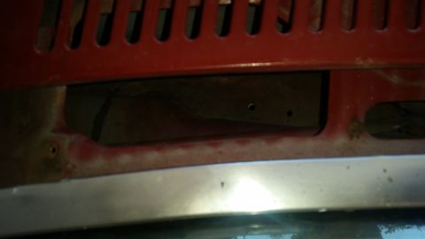 1985 Ford Bronco - Detail shot of a vehicle's front grille area, showing a section with red paint and a dark opening.
