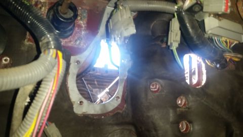 1985 Ford Bronco - This image shows the interior of a vehicle's firewall with various electrical connections and a hole cut through for components.