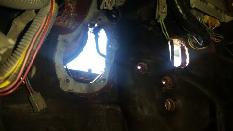 1985 Ford Bronco - Close-up view of a vehicle's interior firewall, showing wiring and cutouts for components.