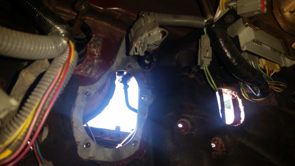 Interior view of vehicle firewall with exposed wiring and grommets