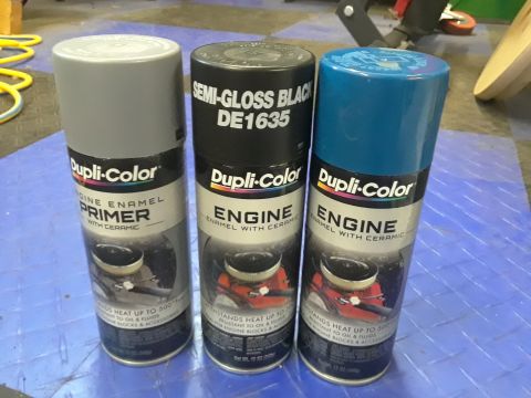 1985 Ford Bronco - Three cans of Dupli-Color engine enamel spray paint are lined up, including primer, semi-gloss black, and a bright blue.