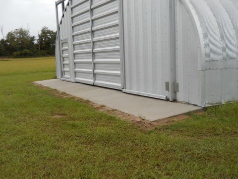 1992 Ford Bronco - A large metal Quonset hut building with a concrete ramp and sliding doors is shown from the side.