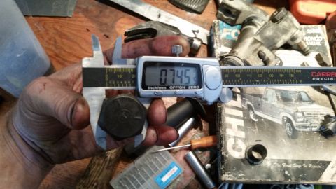 1985 Ford Bronco - A close-up of a caliper measuring a bolt, with a diagram of a pickup truck visible in the background.