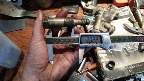 1985 Ford Bronco - A close-up shot shows a bolt being measured with digital calipers, with a Ford Bronco manual in the background.