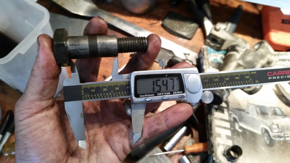 Bolt measured with digital calipers showing 1.547 inches