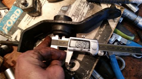 1985 Ford Bronco - A digital caliper measures a metal part on a workbench with tools and documentation in the background.