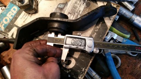 1985 Ford Bronco - A part is measured with a digital caliper, with a Ford manual visible in the background.