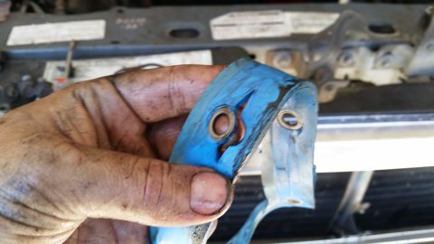 1985 Ford Bronco - Close-up of a dirty hand holding a blue engine component.