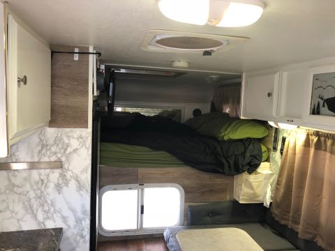 1992 Jeep Wrangler - The interior of a camper shows sleeping accommodations and storage cabinets.
