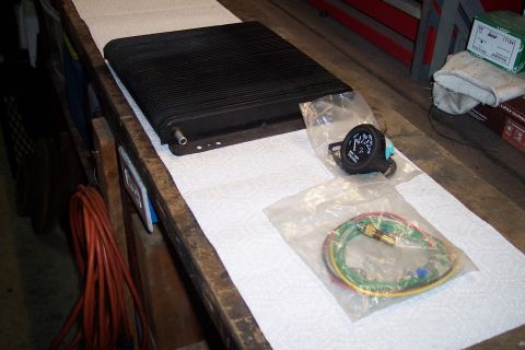 1995 Ford Bronco - A black radiator and a gauge kit are laid out on a workbench, ready for installation.