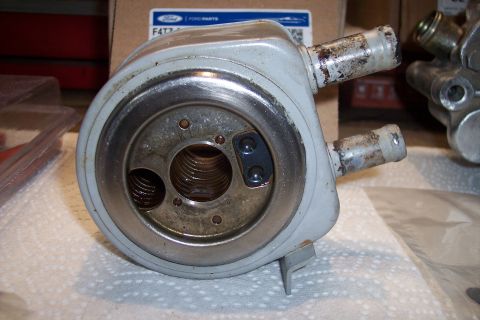 1995 Ford Bronco - A Ford oil cooler part is shown with visible corrosion on its hose connections.
