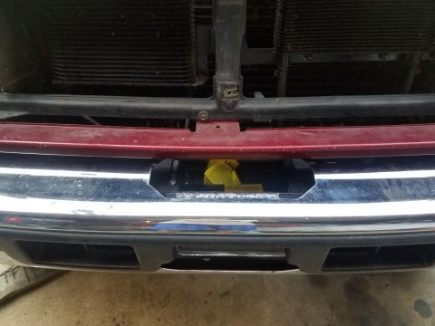 1995 Ford Bronco - Close-up of a vehicle's front end, focusing on the bumper and grille area where a winch is being installed.