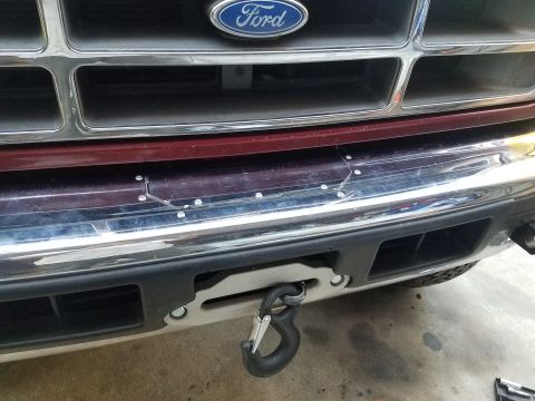 1995 Ford Bronco - Front view of a Ford truck with a winch installed, a chrome grille and maroon body panel.