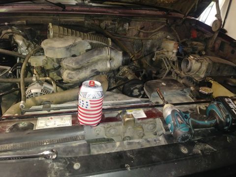 1996 Ford Bronco - The engine bay of a vehicle, a beer koozie and tools, likely undergoing maintenance.