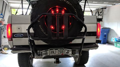 1995 Ford Bronco - The rear of a 1995 Ford Bronco is shown, a spare tire and illuminated brake lights.
