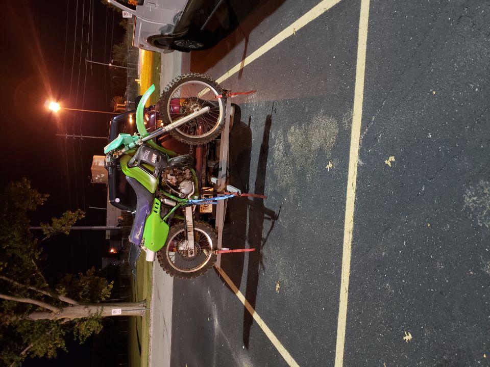 Green dirt bike on trailer, side view