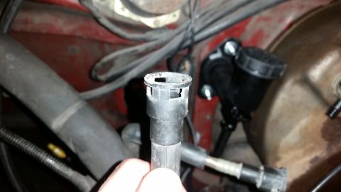 1985 Ford Bronco - A close-up view of a plastic fitting in an engine bay, with a black fluid reservoir visible behind it.