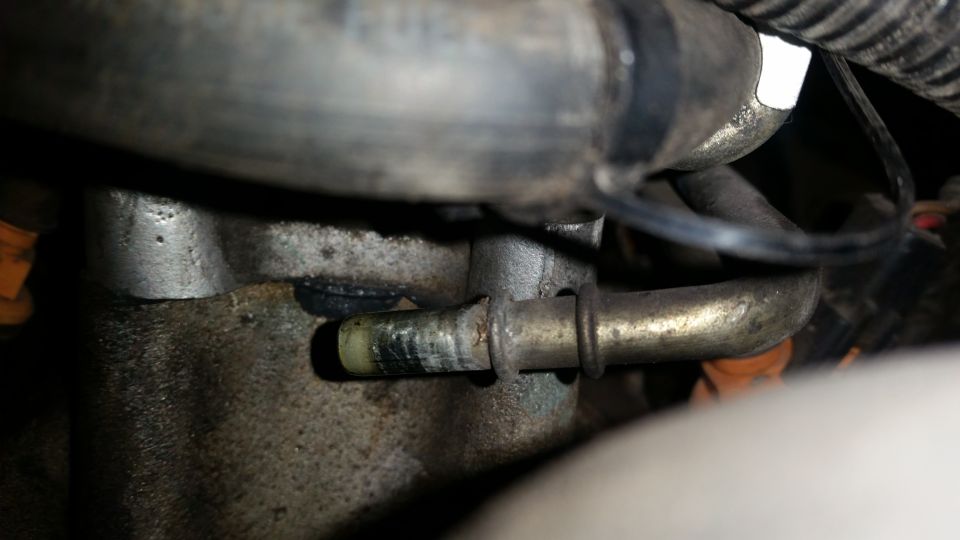 Close-up of a metal engine component with a hose attached and a clamp
