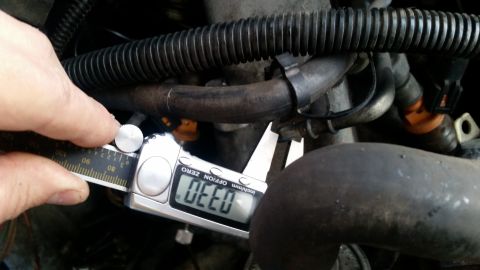 1985 Ford Bronco - A digital caliper is used to measure a component within the engine bay.