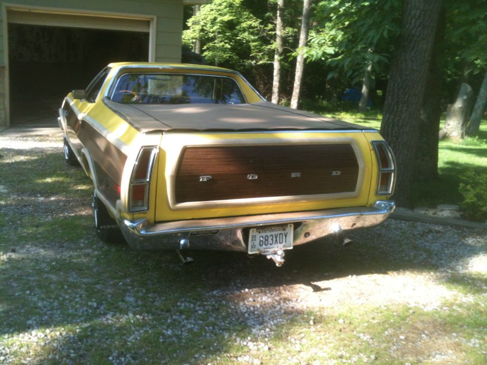 Yellow Ford Ranchero with woodgrain paneling on the tailgate, parked in a driveway