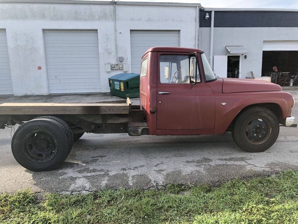 Side view of a red single-cab flatbed truck with dual rear wheels.