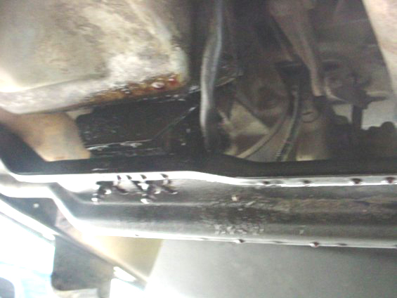 Underside of vehicle showing transmission and oil pan with leaks