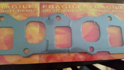 1985 Ford Bronco - A metal gasket with multiple openings is shown against a background with the words "FRAGILE! DO NOT BEND!".