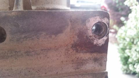 1985 Ford Bronco - A close-up view shows a threaded hole on a rusty metal part, likely from a vehicle's drivetrain or frame. The background is blurred, showin…