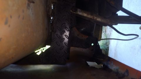 1996 Ford Bronco - This is a close-up, low-angle shot of the undercarriage of a vehicle, focusing on rusty metal components and a section of diamond plate. A…