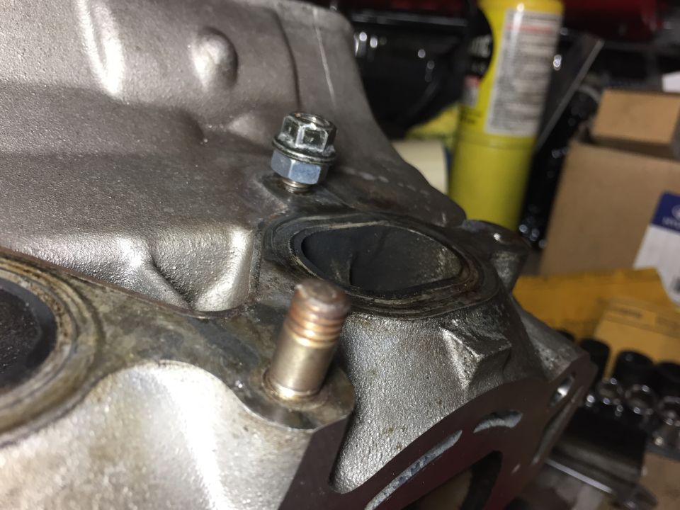 Close-up of engine block exhaust manifold surface with gasket and bolt