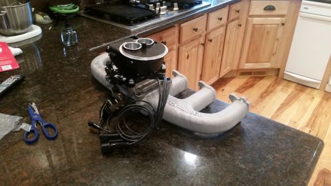 1985 Ford Bronco - A custom aluminum intake manifold with a dual carburetor setup is displayed on a granite countertop in a kitchen setting. The intake manifo…