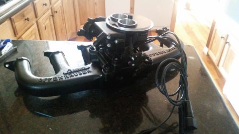 1985 Ford Bronco - A black Offenhauser dual-quad intake manifold with a carburetor is displayed on a dark granite countertop. The manifold has "OFFENHAUSER" c…