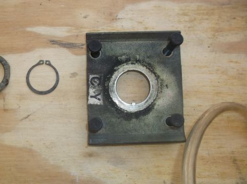 1979 Ford Ranchero - A close-up shot shows a metal plate with a circular opening and four bolts, along with a C-clip and a section of clear tubing. The plate ha…